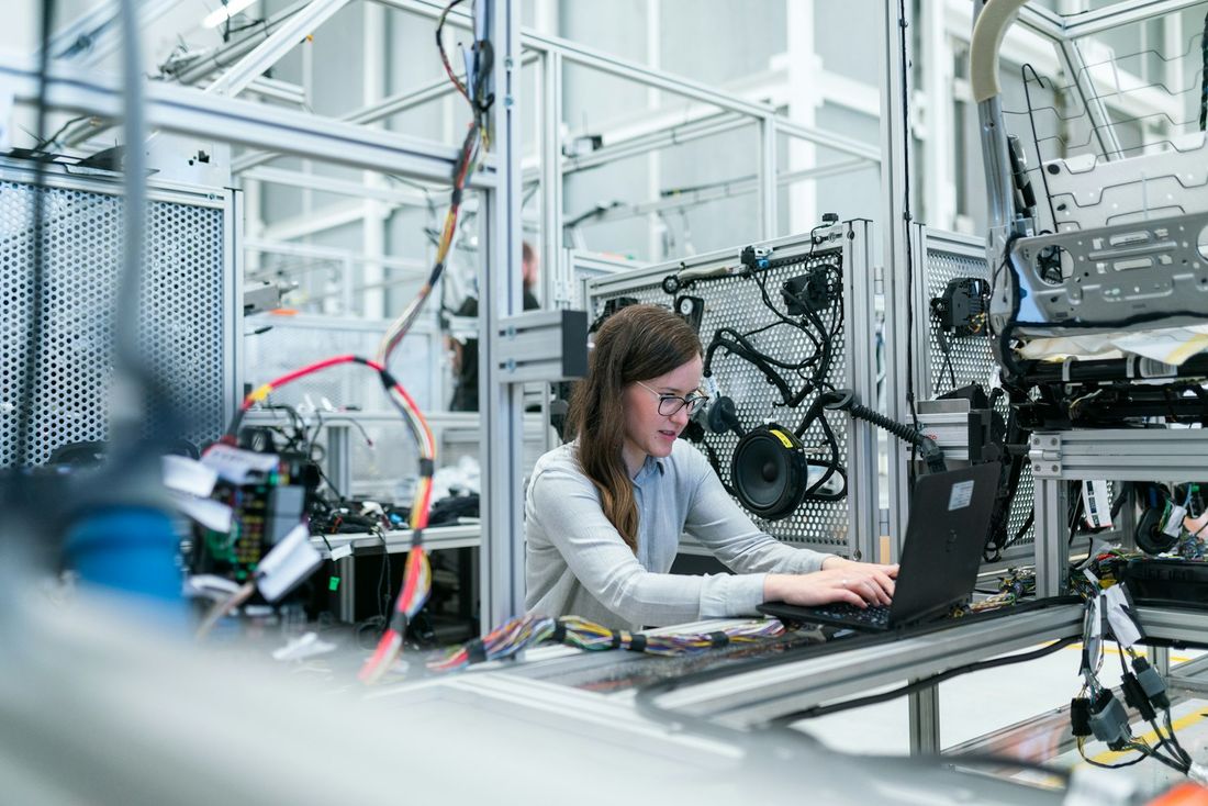 An engineer working at a laptop beside production equipment